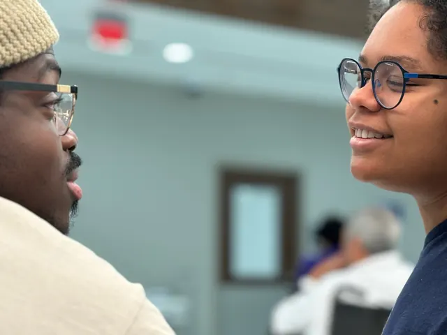 Nicole, in glasses, smiles mid-conversation with Timothy in a beanie.